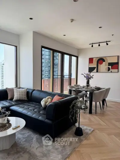 Stylish modern living room with black leather sofa and dining area, city view.