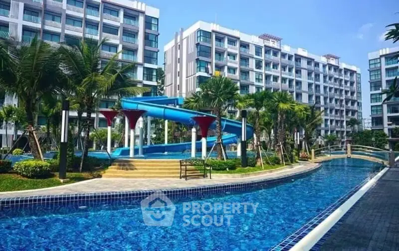 Luxurious condominium with stunning pool and water slide, surrounded by lush greenery and modern architecture.