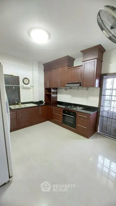 Spacious kitchen with modern wooden cabinets and gas stove in a bright home.