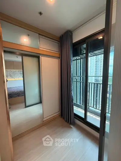 Modern bedroom with mirrored closet and balcony view in high-rise apartment