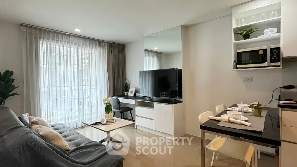 Modern living room with sleek furniture and dining area in open layout apartment.