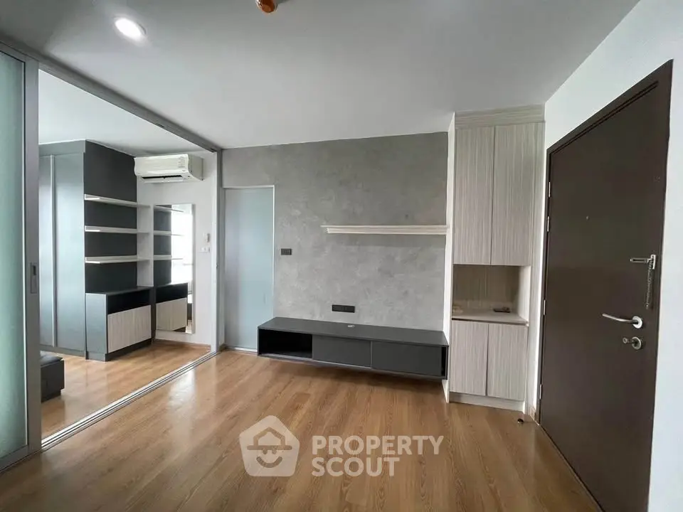 Modern living room with wooden flooring and built-in storage solutions.