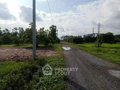 Scenic rural land with gravel road and lush greenery, perfect for development or agriculture.