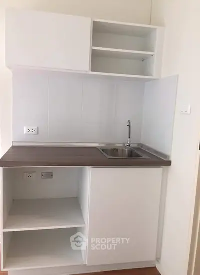 Compact modern kitchen with sleek white cabinetry and stainless steel sink