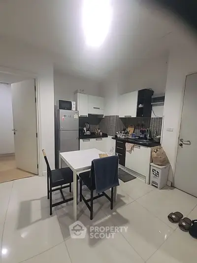 Modern kitchen with dining area, featuring sleek cabinets and appliances.