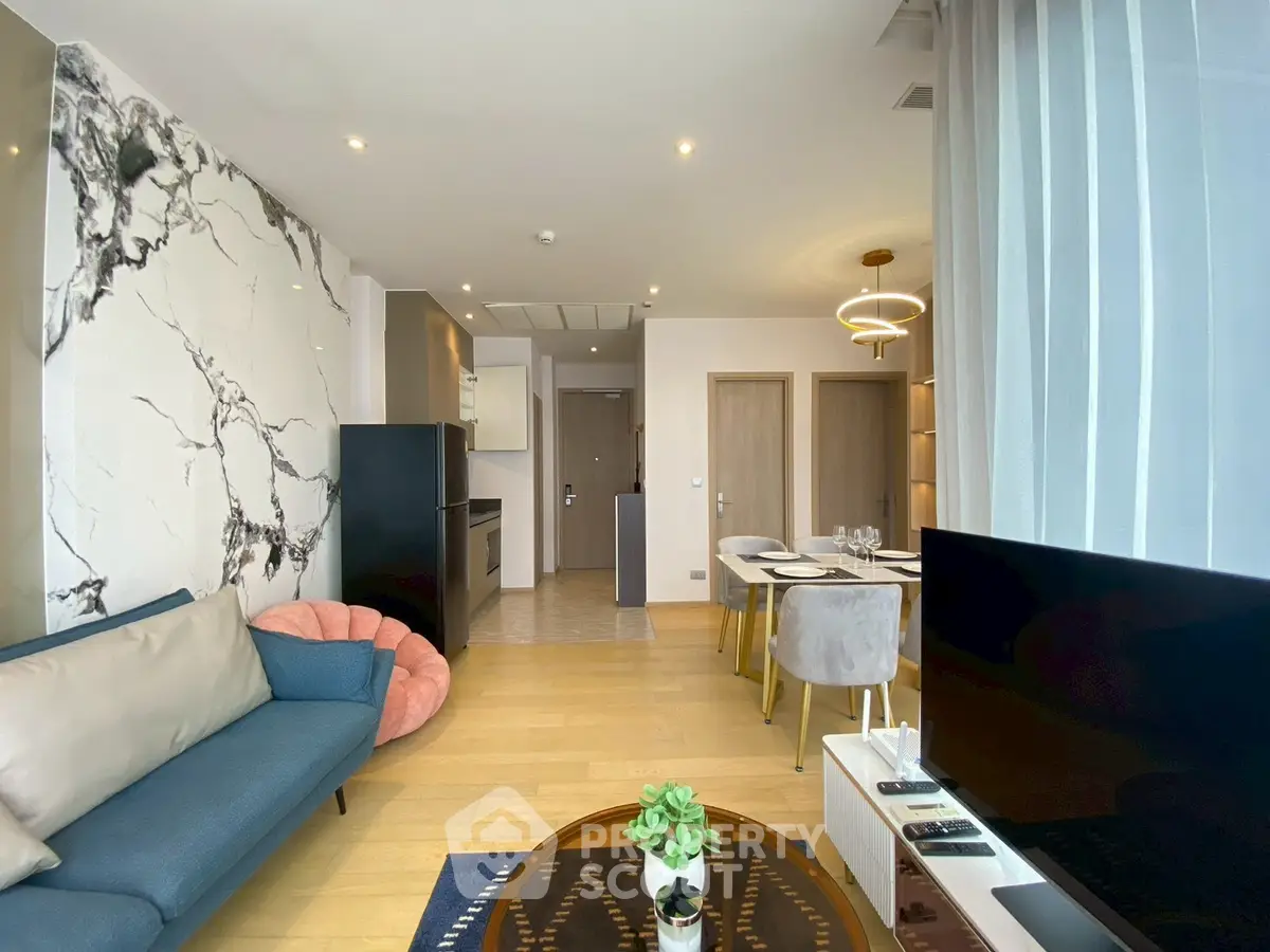 Modern living room with stylish decor and open dining area, featuring elegant furniture and natural light.