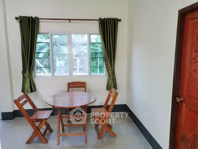 Cozy dining nook with wooden table and chairs, green curtains, and natural light.
