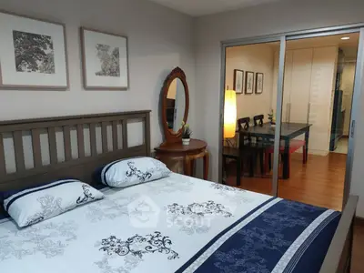 Elegant bedroom with stylish decor and view into dining area through glass doors.