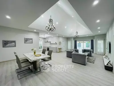 Spacious modern living room with elegant dining area and open layout, featuring stylish chandeliers and natural light.