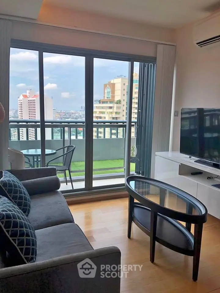 Modern living room with balcony and city view, featuring sleek furniture and large windows.