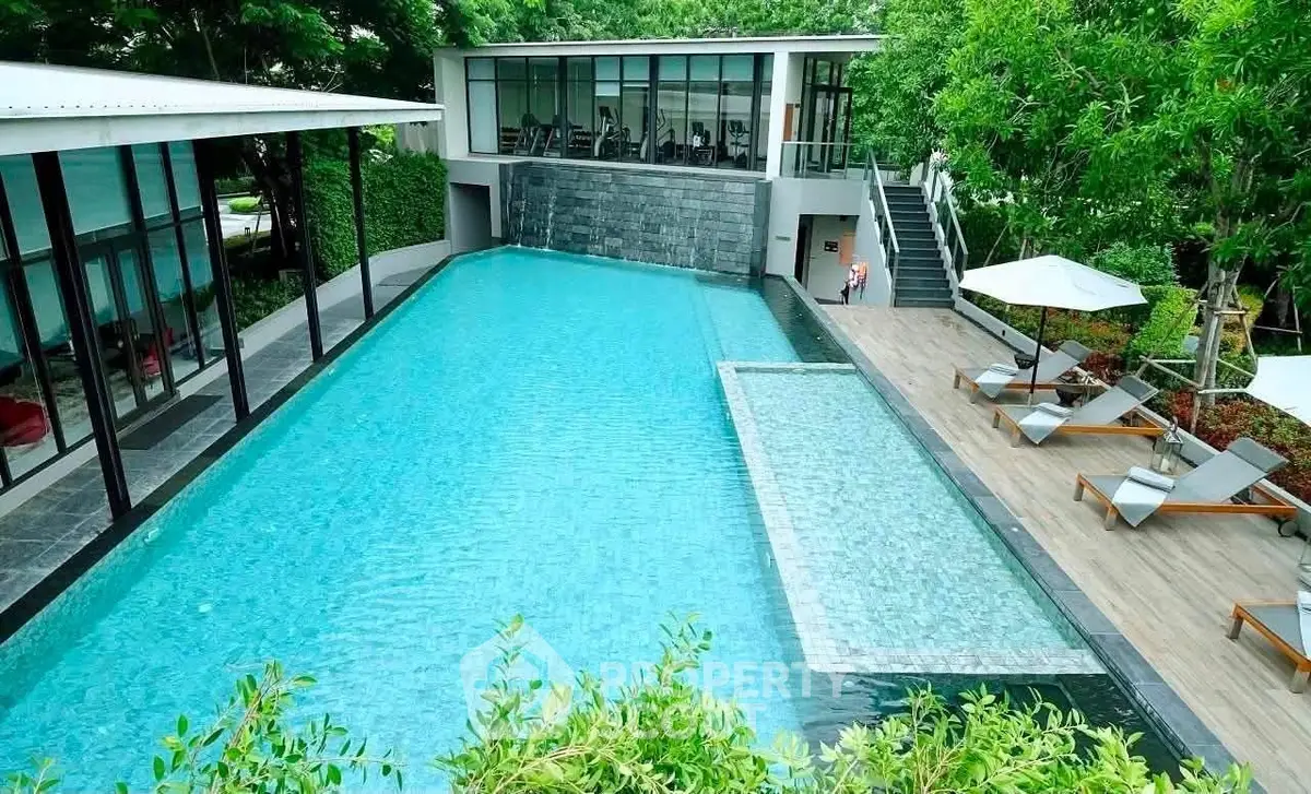 Luxurious modern pool area with sun loungers and lush greenery, perfect for relaxation and leisure.