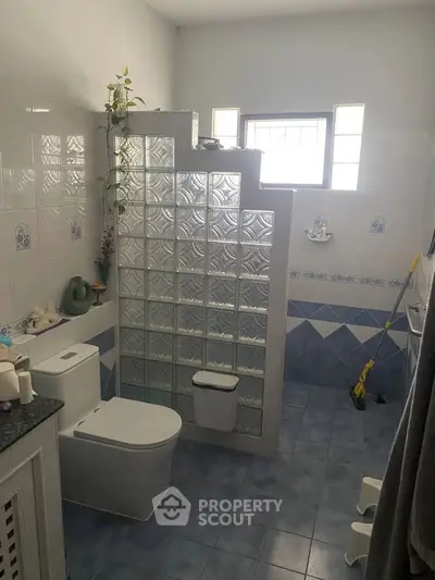 Spacious bathroom with glass block partition and modern fixtures