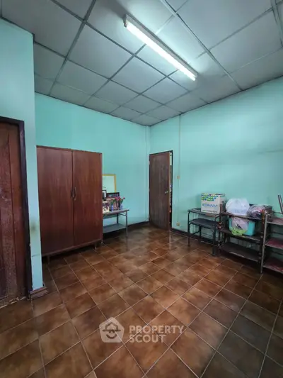 Spacious room with tiled floor and wooden cabinets, ideal for versatile use.