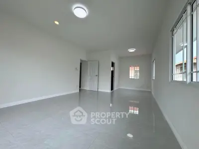 Spacious and bright empty room with glossy tiled flooring and large windows
