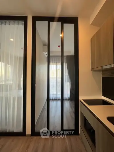 Modern kitchen with sleek cabinetry and large glass doors leading to a bright balcony.