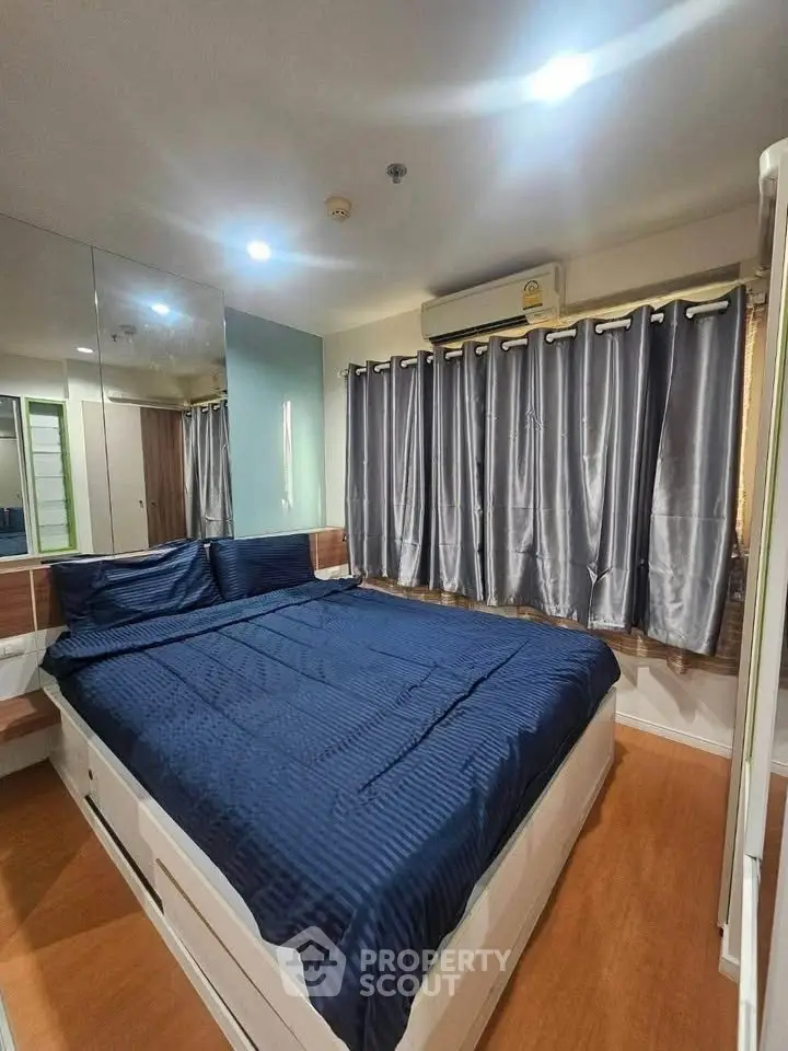 Cozy bedroom with blue bedding and mirrored wall, perfect for relaxation.