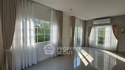 Spacious living room with large windows and elegant curtains, featuring abundant natural light.