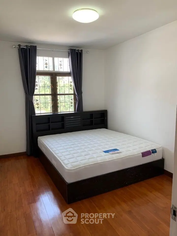 Spacious bedroom with hardwood floors and large window for natural light.
