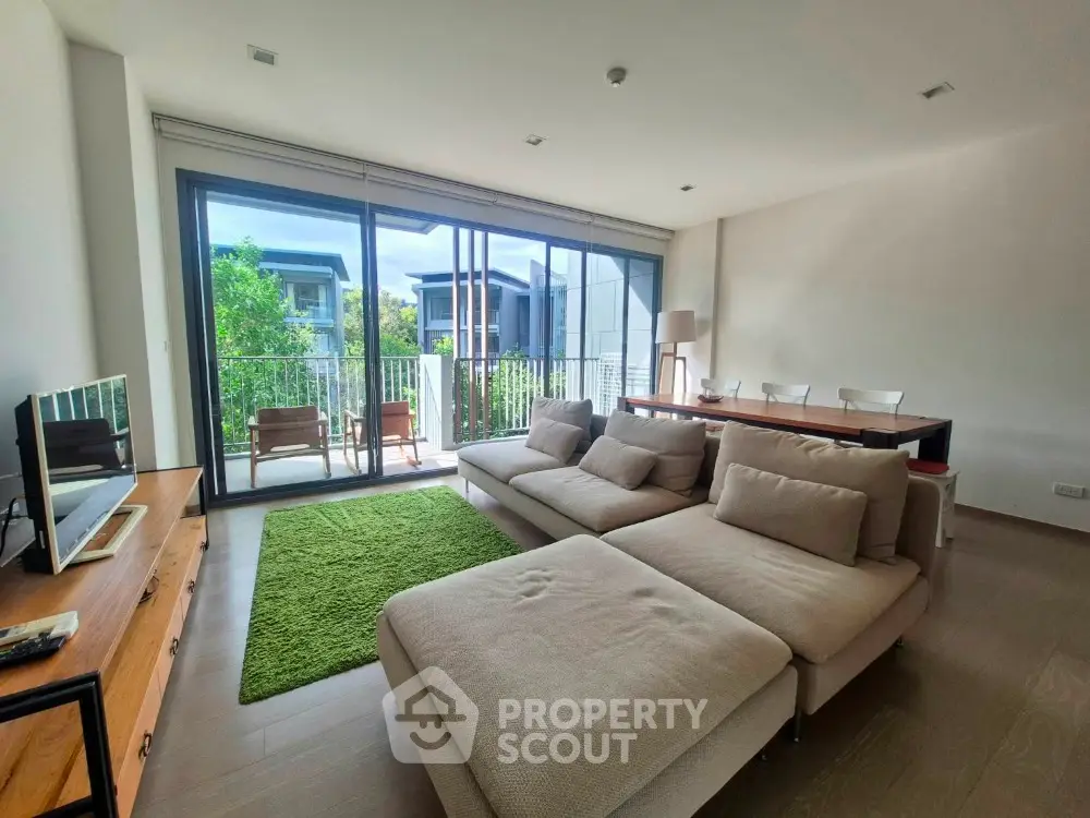 Spacious living room with modern furniture and large windows overlooking greenery.