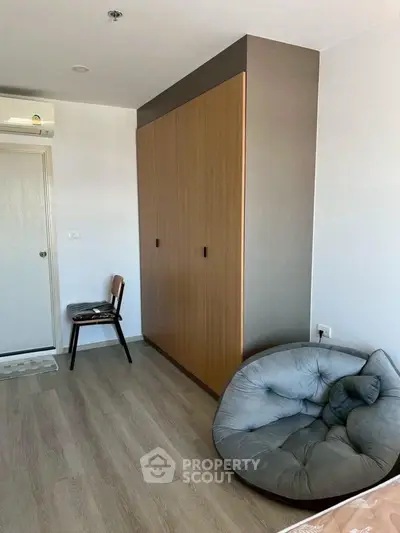 Cozy bedroom with modern wardrobe and stylish chair, perfect for relaxation.