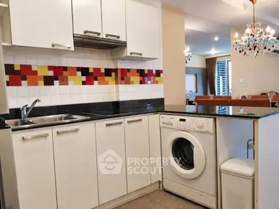 Modern kitchen with washing machine and colorful backsplash in open layout design.