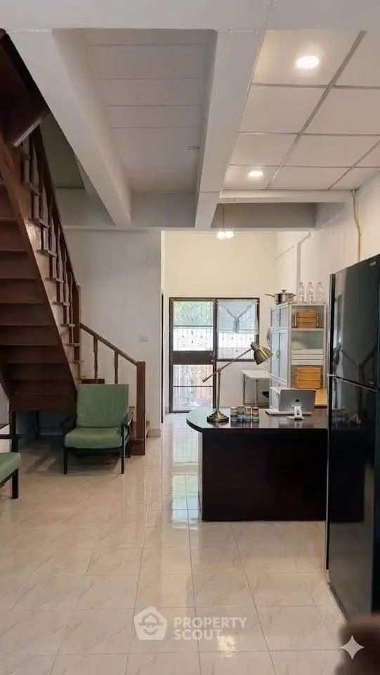 Spacious open-plan living area with modern kitchen and wooden staircase, perfect for family gatherings.