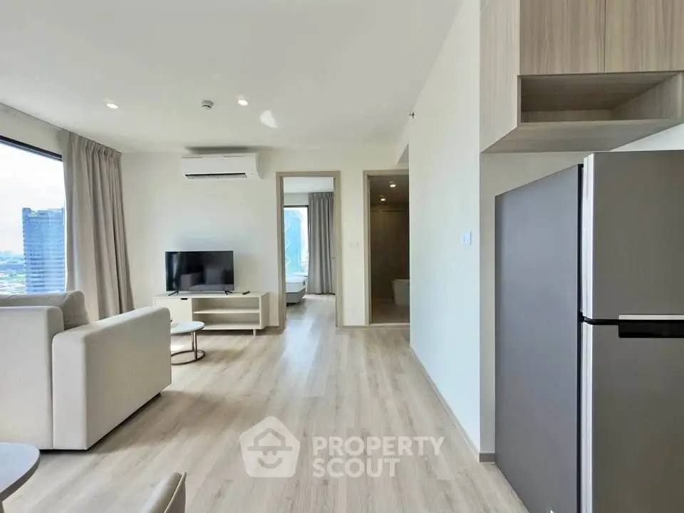 Modern living room with sleek furniture and large windows offering city views.