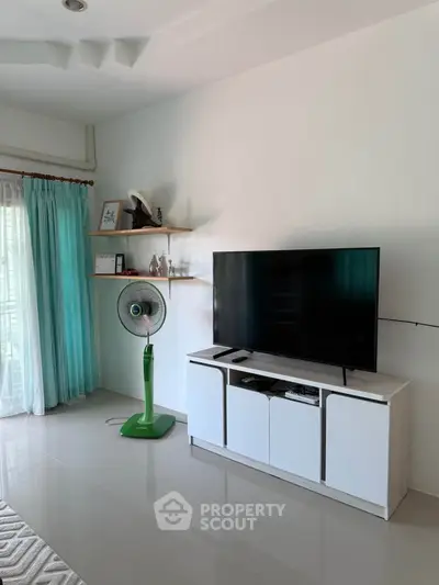 Modern living room with sleek TV stand, large flat-screen TV, and stylish decor, perfect for relaxation and entertainment.