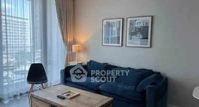 Chic living room with cozy blue sofa, stylish decor, and large window offering natural light.