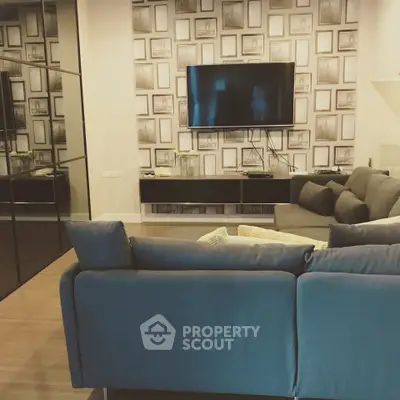Modern living room with stylish decor and wall-mounted TV, featuring a cozy sectional sofa and elegant wall art.