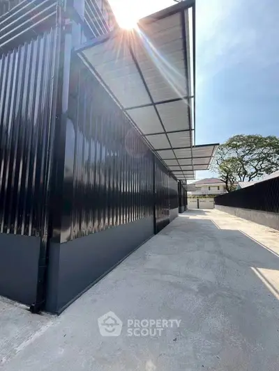 Modern industrial-style building exterior with sleek black metal siding and sunlit canopy.
