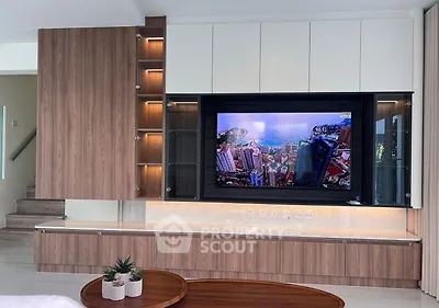Modern living room with built-in wooden cabinetry and large TV, showcasing sleek design and functionality.