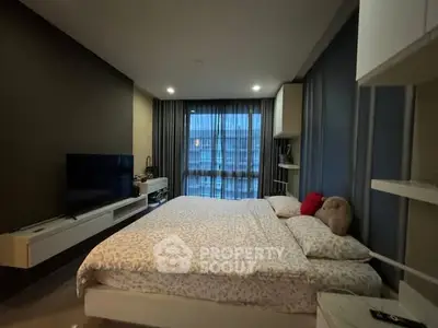 Modern bedroom with large bed and TV, featuring stylish decor and ample natural light.