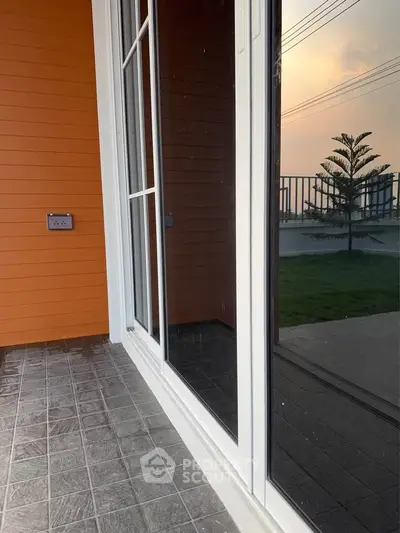 Modern patio with sliding glass doors and garden view at sunset.