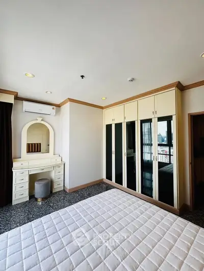 Spacious bedroom with built-in wardrobe and vanity in modern apartment