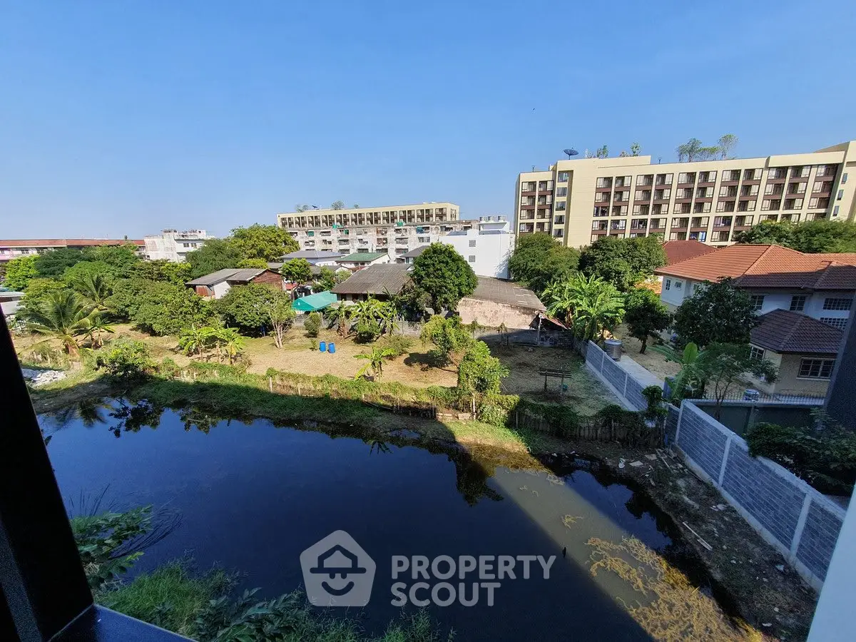 Scenic view of residential buildings and lush greenery by a tranquil pond