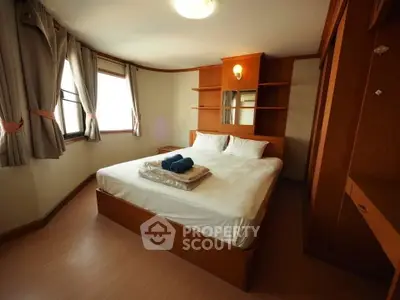 Cozy bedroom with wooden furniture and natural light, perfect for relaxation.