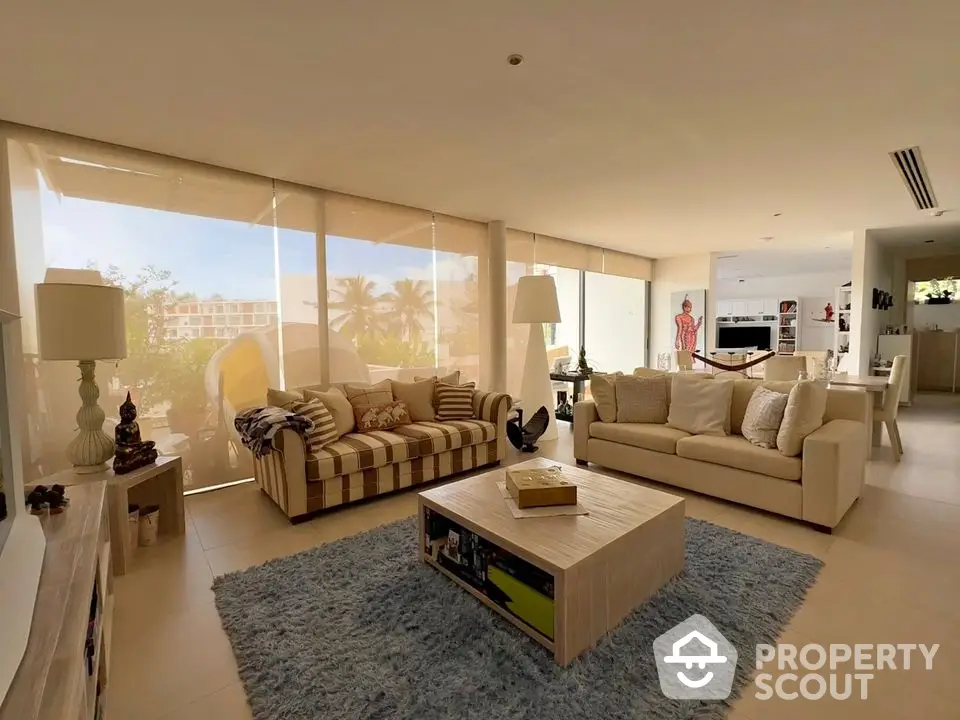 Spacious living room with modern decor and large windows offering natural light and garden view.