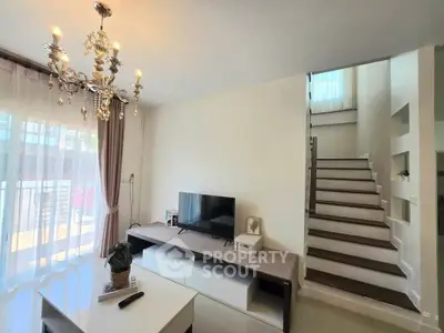 Elegant living room with chandelier and modern staircase in a bright, airy home.