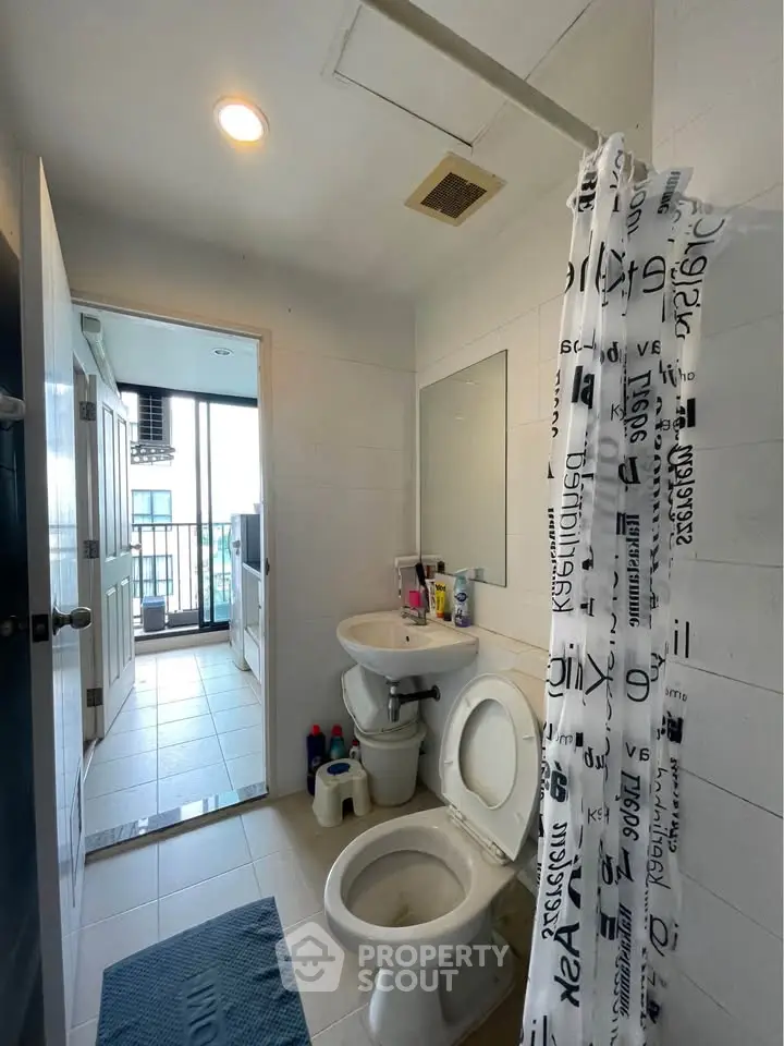Modern bathroom with shower curtain and balcony view, featuring sleek fixtures and bright lighting.