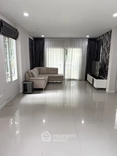 Spacious modern living room with elegant sofa and large windows for natural light.