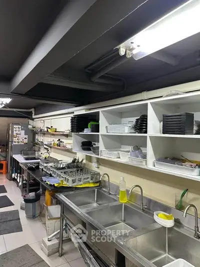 Spacious commercial kitchen with stainless steel sinks and ample shelving.