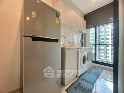 Modern kitchen with stainless steel fridge and washing machine in high-rise apartment.