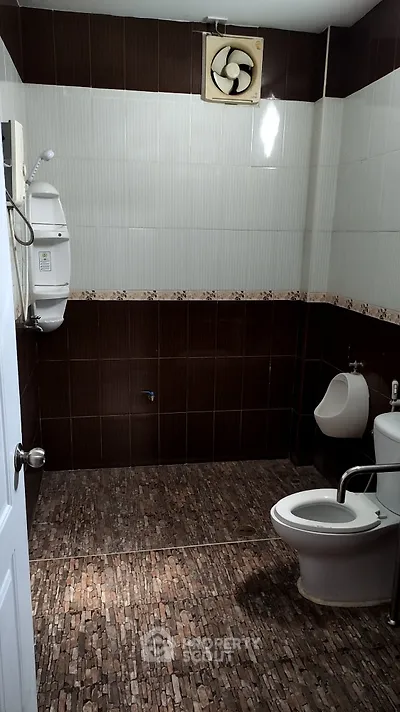 Modern bathroom with tiled walls and floor, featuring a urinal and toilet.