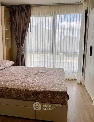Cozy bedroom with large window and elegant curtains, offering a serene and inviting atmosphere.