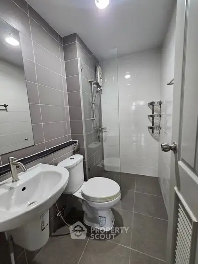 Modern bathroom with sleek fixtures and glass shower enclosure in contemporary apartment.