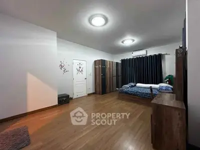 Spacious bedroom with wooden flooring and modern furnishings, perfect for comfort and relaxation.