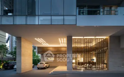 Modern building entrance with luxury cars and sleek architectural design.