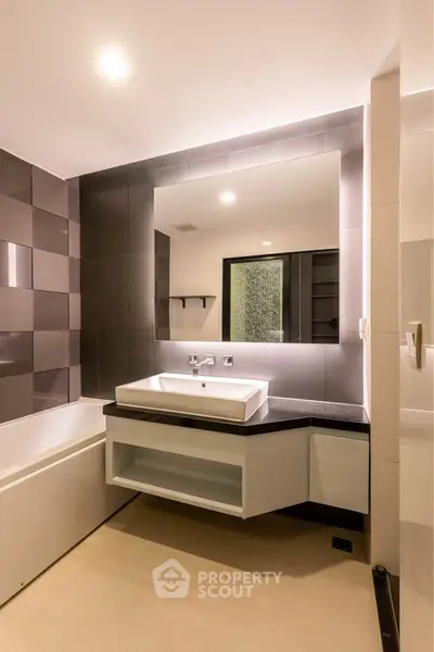 Modern bathroom with sleek design and spacious layout, featuring a large mirror and stylish sink.