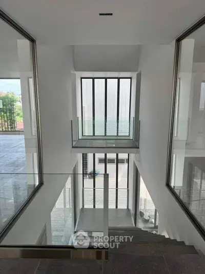Modern minimalist staircase with glass railings and large windows offering natural light.